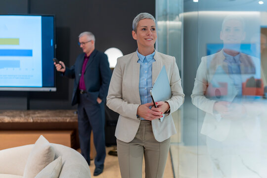 Confident businesswoman holding laptop in modern office