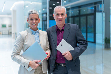 Business professionals standing in office holding devices