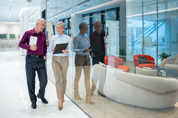 Business colleagues discussing project while walking in modern office