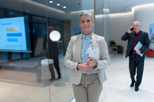 Confident business woman holding tablet in modern office