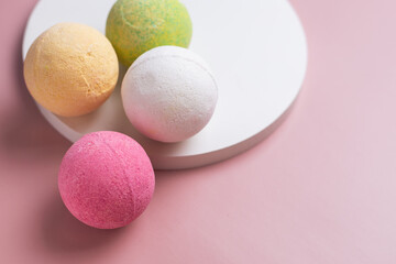 Bath bombs in pink, white, green, and yellow on a pink background. At-home spa treatments for relaxation and restoration. Fizzing bath bombs for aromatherapy and skin care. Cosmetology product