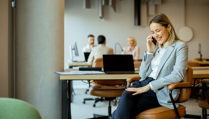 Business woman talking on phone in modern office setting during daytime