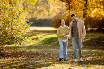 Couple enjoying a sunny autumn stroll through a colorful park filled with leaves