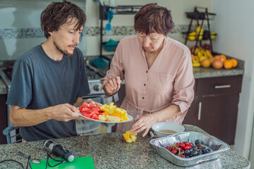 Older woman cooking lunch together with her adult son in the kitchen, enjoying a warm family moment. Home lifestyle, bonding and everyday living concept, representing connection, teamwork and positive