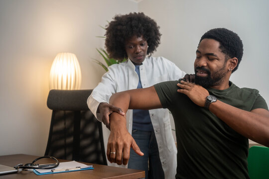Physiotherapist doing healing treatment on man's shoulder