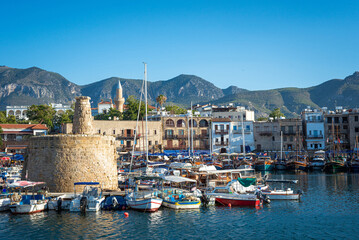 Scenic view of Kyrenia harbour in Cyprus, featuring the historic castle, numerous boats, and a stunning mountain range in the background