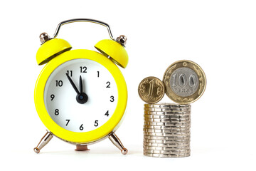 Coins of 1 and 100 Kazakhstani tenge and alarm clock