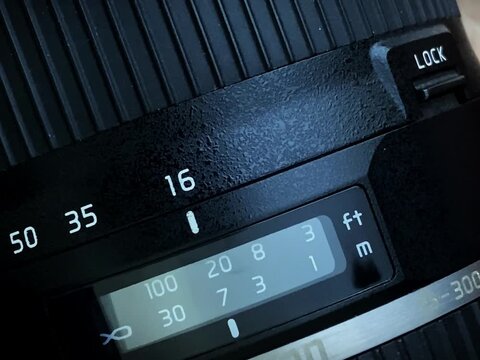 Professional photographer adjusting aperture ring on a vintage camera lens, close-up f-stop scale.