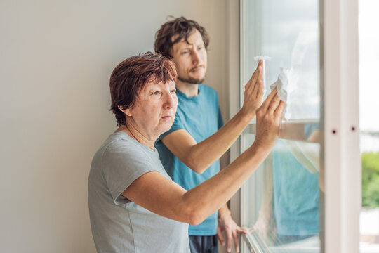 Older woman and her adult son cleaning the house together, sharing teamwork and family cooperation. Home care, organization and lifestyle concept, representing support, connection and everyday