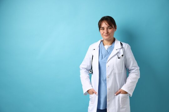 Doctor in medical uniform with stethoscope on light blue background, space for text