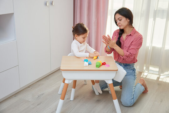 Mother and daughter playing with colorful play-doh modeling clay at a small table