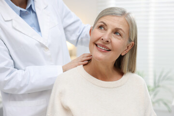 Fototapeta premium Doctor putting hearing aid into patient's ear in clinic, closeup