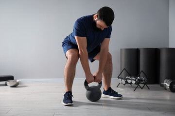 Strong man exercising with kettlebell in gym