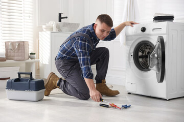 Repairman fixing broken washing machine at home
