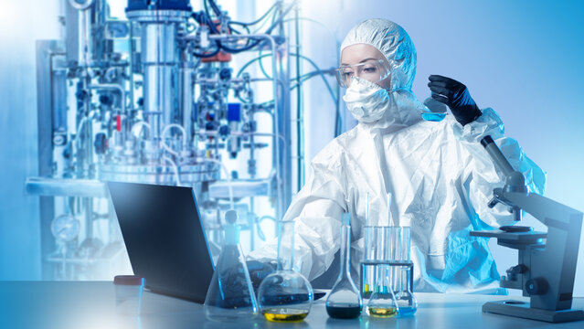 Biochemical research specialist analyzes samples in a sterile lab, operating equipment and recording experimental data to support industrial biotechnology processes.