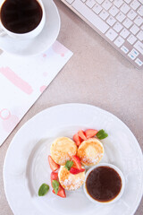 Cheesecakes with strawberries and jam. Healthy and nutritious breakfast. Computer keyboard is on the table. Concept of a business breakfast. Top view. Flat lay.