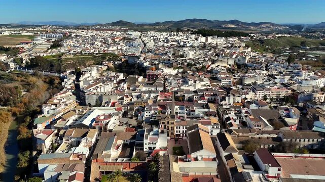 Aerial drone view of Puente Genil Andalusia Spain with Teatro Circo and church towers among whitewashed houses on sunny day over historic town