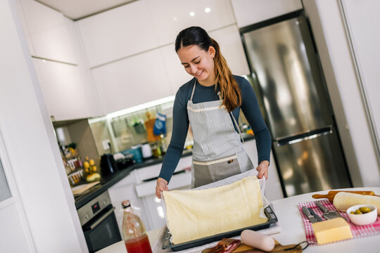 Young woman preparing pizza dough in baking tray - Powered by Adobe