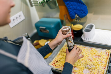 Fototapeta premium Young woman sprinkling salt on pizza