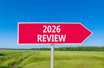 2026 Review symbol. Concept words 2026 Review on beautiful red road sign. Beautiful green grass field forest and blue sky background. Business and 2026 review concept. Copy space.