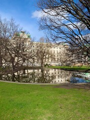 Elegant historic palace with garden and tree reflections in calm water on a sunny day