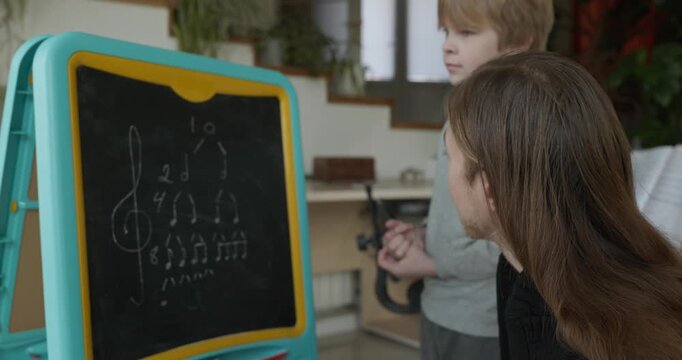 Male Teacher Gives Music Lesson for a Child. Man is Teaching Kid to Play Musical Instrument. 4K 10-bit