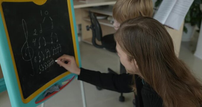 Male Teacher Gives Music Lesson for a Child. Man is Teaching Kid to Play Musical Instrument. 4K 10-bit