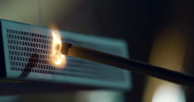 Slow motion close-up of a match being struck on a matchbox and bursting into flame at 1000 fps. Warm tones, detailed sparks, slow-motion ignition.