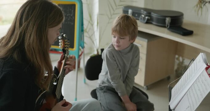 Male Teacher Gives Music Lesson for a Child. Man is Teaching Kid to Play Musical Instrument. 4K 10-bit