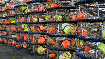 Row of stacked crab pot traps with colored floats on pier