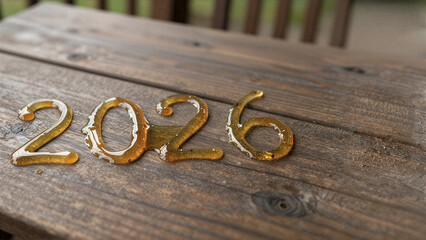 Number 2026 formed with golden honey on wooden surface