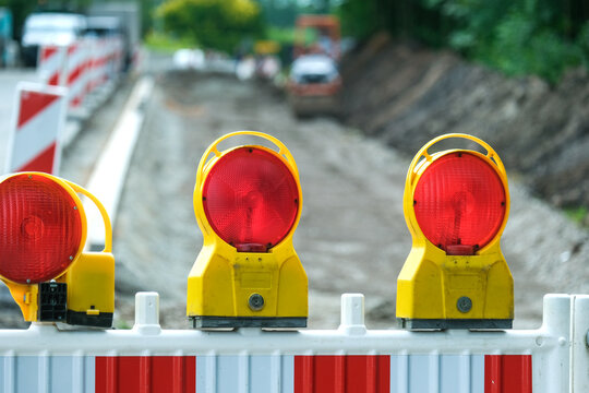 Detail Blick auf eine Absperrung einer Stra&szlig;enbaustelle mit Sanierungsarbeiten an aufgerissener Stra&szlig;e, Baumaterial, Absperrung, Maschinen und Erdarbeiten, selektiver Fokus