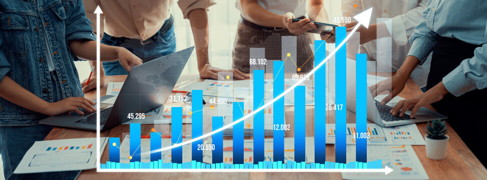 A diverse team collaborates on data analysis and chart presentation in a modern office setting, showcasing growth and teamwork through technology and documents. Amity