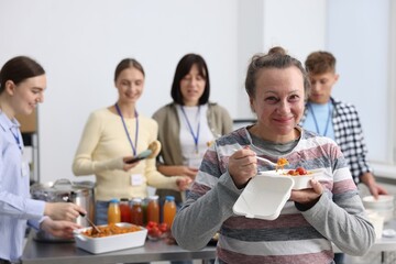 Volunteers giving food to homeless people in shelter