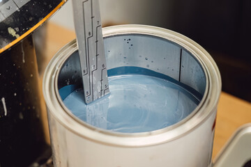 Careful mixing and measuring of automotive paint in a can for precise color matching. Chemistry and technical preparation for high quality body repair and professional painting service maintenance.