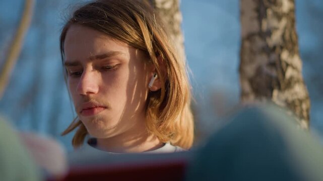 young person deeply engaged in study session, caucasian adolescent absorbed in reading under bright sunlight, teenage individual immersed in closeup study with soft sunlight on face