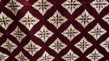 velvet fabric with a repeating diamond pattern made of ornate cream and gold motifs arranged in neat rows across the surface, useful for backgrounds