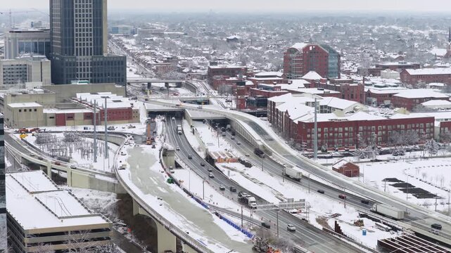 Interstate i70 and i71 highway system and roadway construction by car traffic on multi-lane roads near Columbus, Ohio during a snowy cold winter day from a drone shot and aerial view of cars and snow