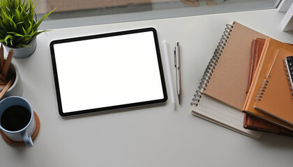 Workspace with Tablet and Accessories: A tidy workspace featuring a blank tablet screen, pens, notebooks, and a cup of coffee, perfect for productivity and creative pursuits.