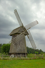 Fototapeta premium Old Wooden Windmill in Countryside Field Under Overcast Sky