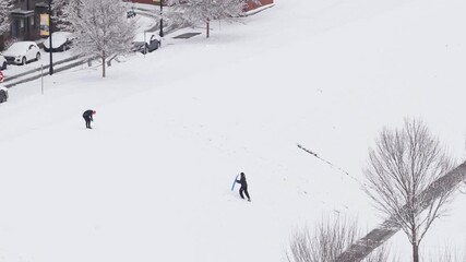 One person playing in the snow and hiking up hill holding a snowboard to play in snow-covered environment in Columbus, Ohio weather and winter season on day off cause snowstorm from drone shot aerial