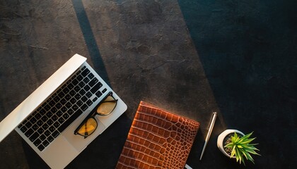 Workspace essentials: a meticulously arranged workspace features a laptop, glasses, journal, pen, and plant, evoking productivity and focus.