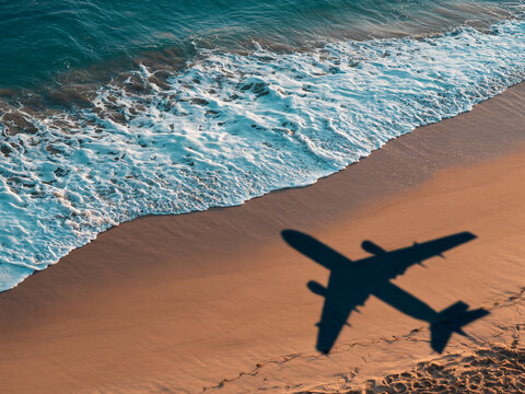Escape to paradise with airplane shadow over sandy beach and ocean waves, dream vacation is about to begin