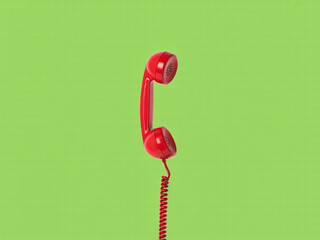 Vibrant red retro telephone receiver with coiled cord for communication needs in a modern world