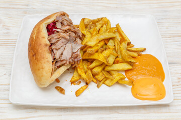 Sandwich kebab avec des frites et sauces dans une assiette