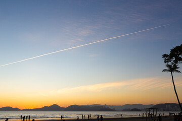 Sunset sky with airplane contrail over Santos beach, Brazil