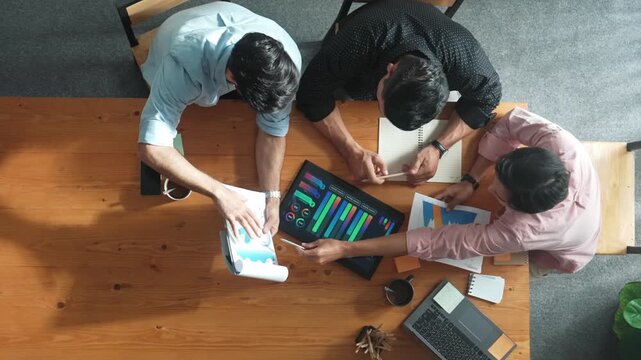Time lapse of manager explain financial graph to colleague at meeting room. Top aerial view of diverse marketing team sharing idea and planning strategy while sitting at meeting table. Convocation.