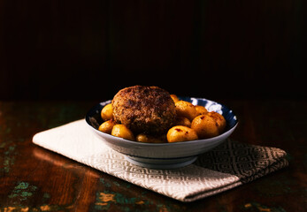 Fried meatballs with potatoes on a rustic background. Selective and soft focus.	