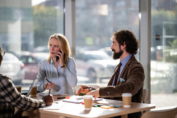 Business colleagues having a meeting while a woman is speaking on phone