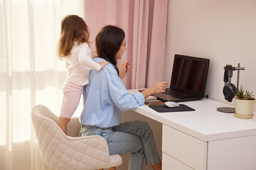Happy mother hugging daughter during remote work from a home office